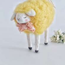 Load image into Gallery viewer, A close up of a yellow, vintage style needle felted spun cotton sheep ornament. White flowers sit behind it, against a white background. Pic 1 of 7.