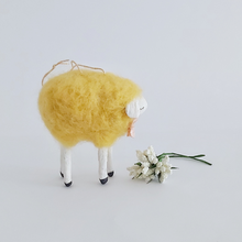 Load image into Gallery viewer, An opposite side view of a yellow, vintage style needle felted spun cotton sheep ornament. White flowers sit in front of her, against a white background. Pic 6 of 7.