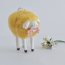 Load image into Gallery viewer, Another closer view of a yellow, vintage style needle felted spun cotton sheep ornament. White flowers sit next to her, against a white background. Pic 4 of 7.