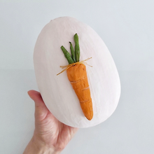 Load image into Gallery viewer, A hand holding a light pink, paper mache egg box. A spun cotton carrot adorns the cover. Pic 8 of 12.