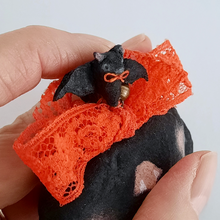 Load image into Gallery viewer, A close-up photo of a tiny spun cotton bat hanging from an orange lace bow. Pic 3 of 7.