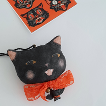 Load image into Gallery viewer, A vintage style, spun cotton black cat ornament on a white background. A print of vintage style black cats lays in the background. Pic 5 of 7.