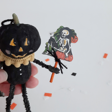 Load image into Gallery viewer, A close-up of a vintage skeleton illustration, held up by a spun cotton black pumpkin man. Pic 5 of 7.