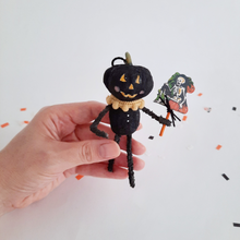 Load image into Gallery viewer, A vintage style, spun cotton black pumpkin man ornament held in hand over Halloween confetti on a white background. Pic 2 of 7.