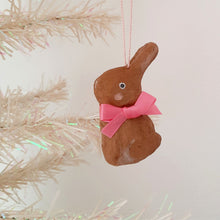 Load image into Gallery viewer, A brown, spun cotton bunny wearing a pink bow dangles from a white tree, against a light background.