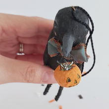 Load image into Gallery viewer, A close up view of the silver tinsel inside a spun cotton jack-o-lantern pail held by spun cotton crow ornament. Pic 7 of 8.