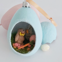 Load image into Gallery viewer, Another close-up of vintage style spun cotton Easter bunny diorama ornament. It lays against pink and light blue egg ornaments, on a white background. Pic 4 of 8.