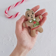 Load image into Gallery viewer, A hand holding a vintage style, spun cotton gingerbread girl ornament. A candy cane lays in the background. Pic 4 of 8.