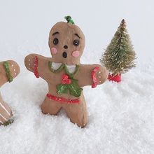 Load image into Gallery viewer, A close-up of a vintage style, spun cotton gingerbread girl ornament. A mini bottle brush tree sits behind her, on fake snow. Pic 5 of 8.