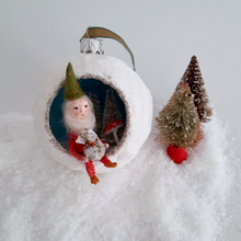 Load image into Gallery viewer, Another view of a vintage style, spun cotton gnome diorama ornament sitting next to two vintage bottlebrush trees. Pic 5 of 5.