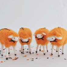 Load image into Gallery viewer, A close view of four vintage style, spun cotton needle felted orange sheep ornaments. They stand on Halloween confetti, against a white background. Pic 1 of 5.