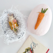 Load image into Gallery viewer, A vintage style, spun cotton bunny ornament laying in a light pink paper mache egg box with white tissue shredding. A vintage Easter card lays below in the photo. Pic 11 of 12.