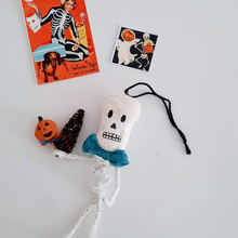 Load image into Gallery viewer, A vintage style, spun cotton pipe cleaner skeleton laying next to vintage skeleton illustrations. Pic 3 of 5.