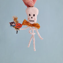 Load image into Gallery viewer, A vintage style, spun cotton pipe cleaner skeleton held against a light blue background. Pic 5 of 5.
