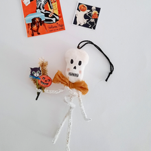 Load image into Gallery viewer, A vintage style, spun cotton pipe cleaner skeleton ornament laying by two vintage skeleton illustrations. Pic 4 of 4.