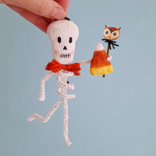 Load image into Gallery viewer, A vintage style, spun cotton skeleton ornament held against a light blue background. Pic 4 of 5.