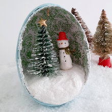 Load image into Gallery viewer, A close view of a vintage style, spun cotton snowman diorama ornament. Two vintage bottlebrush trees sit behind it. Pic 1 of 6.