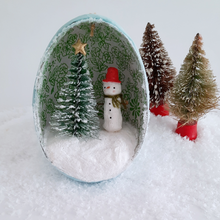 Load image into Gallery viewer, Another view of a vintage style, spun cotton snowman ornament diorama against white fake snow. Two vintage bottlebrush trees sit next to it. Pic 5 of 6.