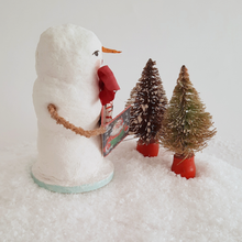 Load image into Gallery viewer, An opposite side view of a vintage style, spun cotton snowman standing behind two vintage bottlebrush trees. Pic 5 of 6.