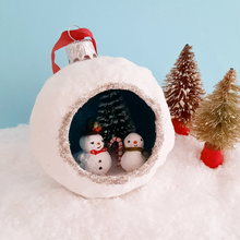 Load image into Gallery viewer, Another closer view of a vintage style, spun cotton snowmen diorama ornament. It sits next to two vintage bottlebrush trees. Pic 2 of 5.