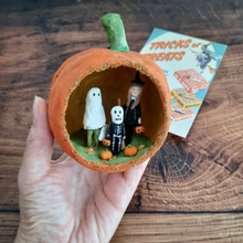 Load image into Gallery viewer, A hand holding a vintage style, spun cotton trick-or-treaters ornament next to a vintage Halloween advert on a wood background. Pic 3 of 7.