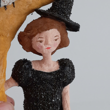 Load image into Gallery viewer, A close-up of the face of a vintage style, spun cotton witch sitting on a moon. Pic 4 of 8.