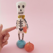 Load image into Gallery viewer, Full shot of spun cotton skeleton, holding candy corn. Photo 2