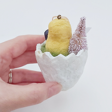 Cargar imagen en el visor de la galería, Back view of a spun cotton chick sitting in a cracked egg. It's held in a hand against a white background. Pic 5 of 6.