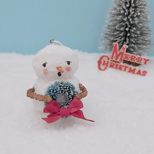 Load image into Gallery viewer, Handmade vintage style spun cotton snowman, holding wreath and standing on snow against a light blue background, by a bottle brush tree and vintage Merry Christmas decoration. Pic 1 of 8.