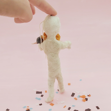 Load image into Gallery viewer, Back view of spun cotton mummy and mouse ornament, standing on Halloween confetti while supported by hand. Pic 7 of 8.