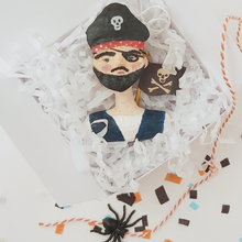 Load image into Gallery viewer, Spun cotton pirate boy ornament, laying in white gift box with white tissue shredding and orange bakers twine. Pic 4 of 7.