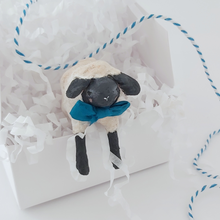 Load image into Gallery viewer, A miniature spun cotton sheep hanging out of a white gift box in white tissue shredding against a white background. Pic 4 of 8.