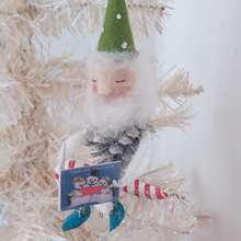 Load image into Gallery viewer, A vintage style spun cotton pine cone elf sitting on a candy cane, hanging from a white Christmas tree. Pic 2 of 10.