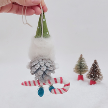 Load image into Gallery viewer, Back view of spun cotton pine cone elf sitting on a spun cotton candy cane. Pic 7 of 10.
