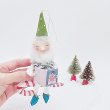 Load image into Gallery viewer, Vintage style spun cotton pine cone elf sitting on a spun cotton candy cane, held in hand for size comparison. Pic 4 of 10.
