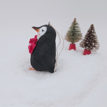 Load image into Gallery viewer, Opposite side view of spun cotton pine cone penguin sitting on fake snow with two miniature bottle brush trees in the distance. Pic 10 of 10.