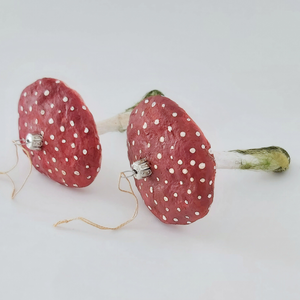 A close up of two spun cotton red mushroom ornaments, against a white background. Pic 3 of 5. 