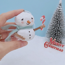Load image into Gallery viewer, Vintage style spun cotton snowman, held in hand for size comparison. He's against a light blue background with a bottle brush tree and Merry Christmas sign in the distance. Pic 1 of 7.