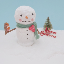 Load image into Gallery viewer, Vintage style spun cotton snowman holding a spun cotton robin on his arm. He sits on snow, against a light blue background and in front of a vintage bottle brush tree and Merry Christmas sign. Pic 1 of 7.