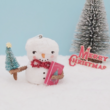 Load image into Gallery viewer, Vintage style spun cotton snowman holding a mini bottle brush tree and box of tinsel. It's set against a light blue background, on snow, with a bottle brush tree and vintage Merry Christmas sign. Pic 1 of 8.