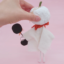 Load image into Gallery viewer, Back view of spun cotton white jack-o-lantern ghost ornament, held in hand against pink background. Pic 7 of 7.