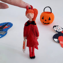 Load image into Gallery viewer, A spun cotton devil girl ornament is held by a finger, with a pumpkin bucket and other vintage '80s Halloween decor in the background.
