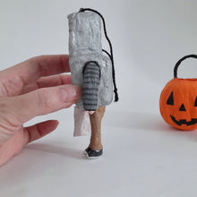 Load image into Gallery viewer, A hand holds a spun cotton robot boy Halloween ornament.  A small orange jack-o'-lantern bucket is blurred in the background on a white surface.
