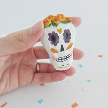 Load image into Gallery viewer, A spun cotton sugar skull, held in hand against a white background. Pic 2 of 5. 
