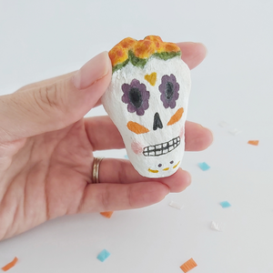 A spun cotton sugar skull, held in hand against a white background. Pic 2 of 5. 