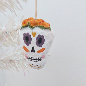A spun cotton sugar skull ornament, hanging on a tree against a white background. Pic 1 of 5.