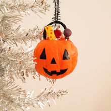 Load image into Gallery viewer, A spun cotton jack-o'-lantern bucket  ornament hanging from a black string on a silver tinsel Christmas tree against a warm beige background
