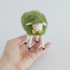A green vintage style needle felted sheep ornament, standing in a hand. Pic 2 of 7. 