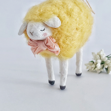 Load image into Gallery viewer, A close up of a yellow, vintage style needle felted spun cotton sheep ornament. White flowers sit behind it, against a white background. Pic 1 of 7. 
