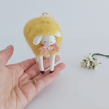 Load image into Gallery viewer, A yellow, vintage style needle felted spun cotton sheep standing on a hand. White flowers sit nearby, against a white background. Pic 2 of 7. 
